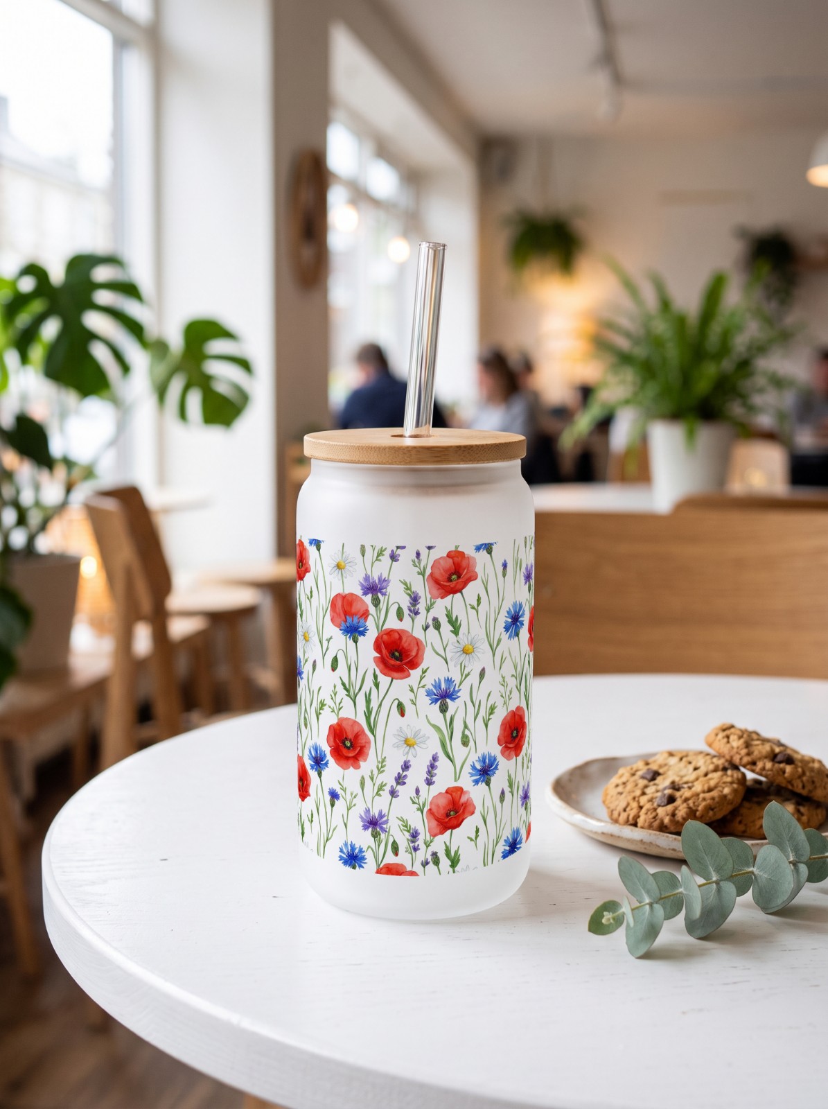 16 oz Frosted Glass Can with Bamboo Lid in a Café showing a watercolor wildflower wrap
