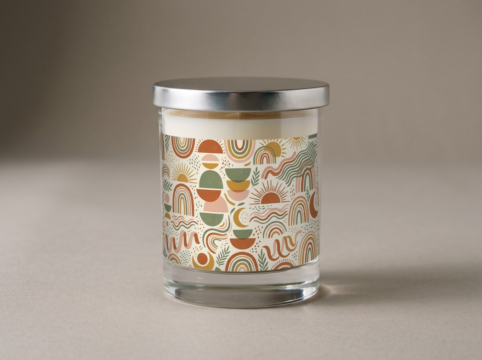 Clear Glass Candle with a Silver Lid in the Studio showing a boho mid-century arches and suns label