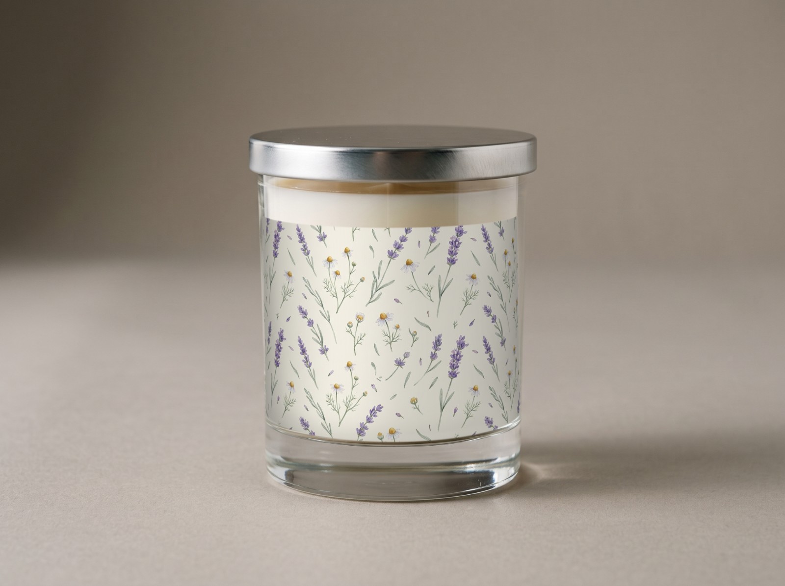 Clear Glass Candle with a Silver Lid in the Studio showing a watercolour lavender and chamomile label