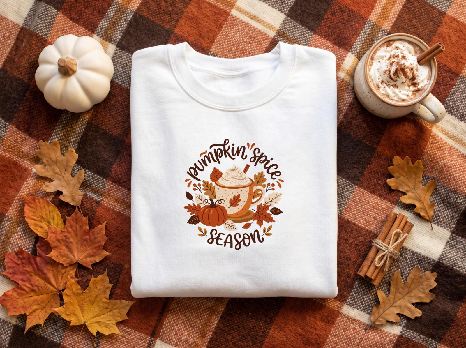 Folded White Sweatshirt Halloween on a Plaid Blanket showing a Pumpkin Spice Season latte design