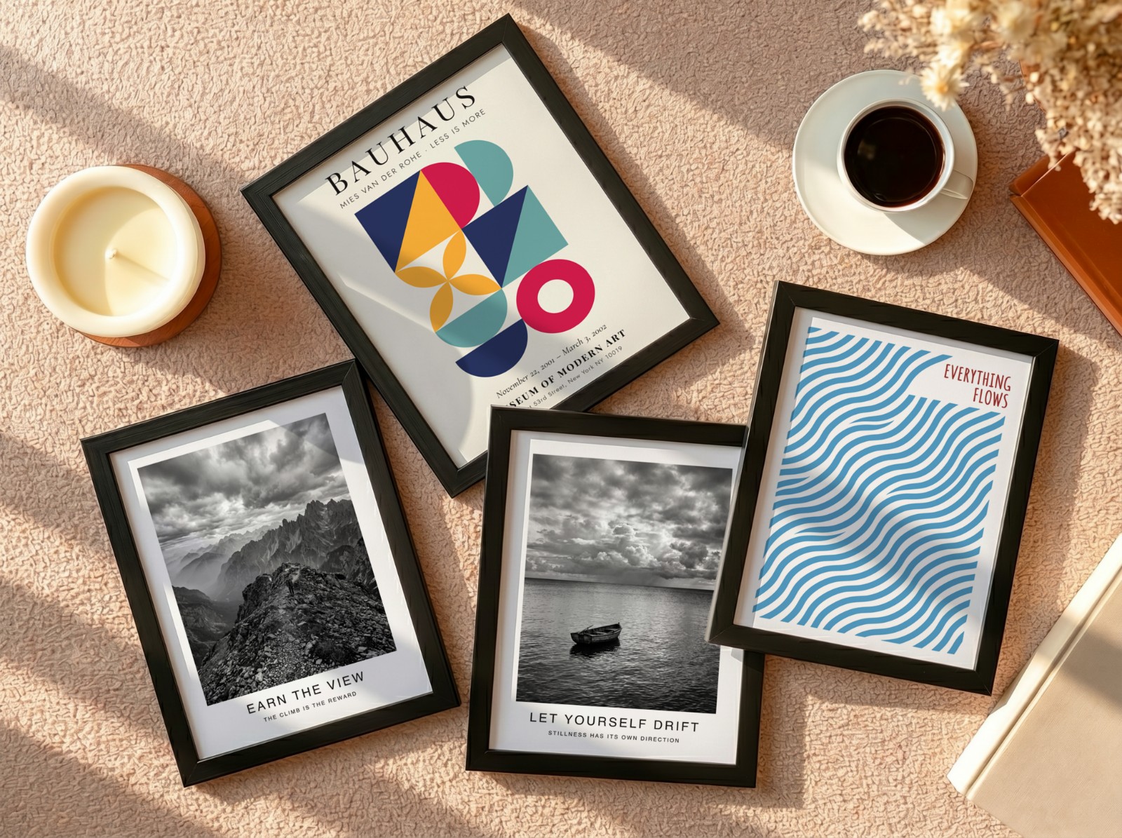 Four Black Frames Flat Lay on Beige Carpet showing an Everything Flows wave print, a black and white mountain print and 2 more designs