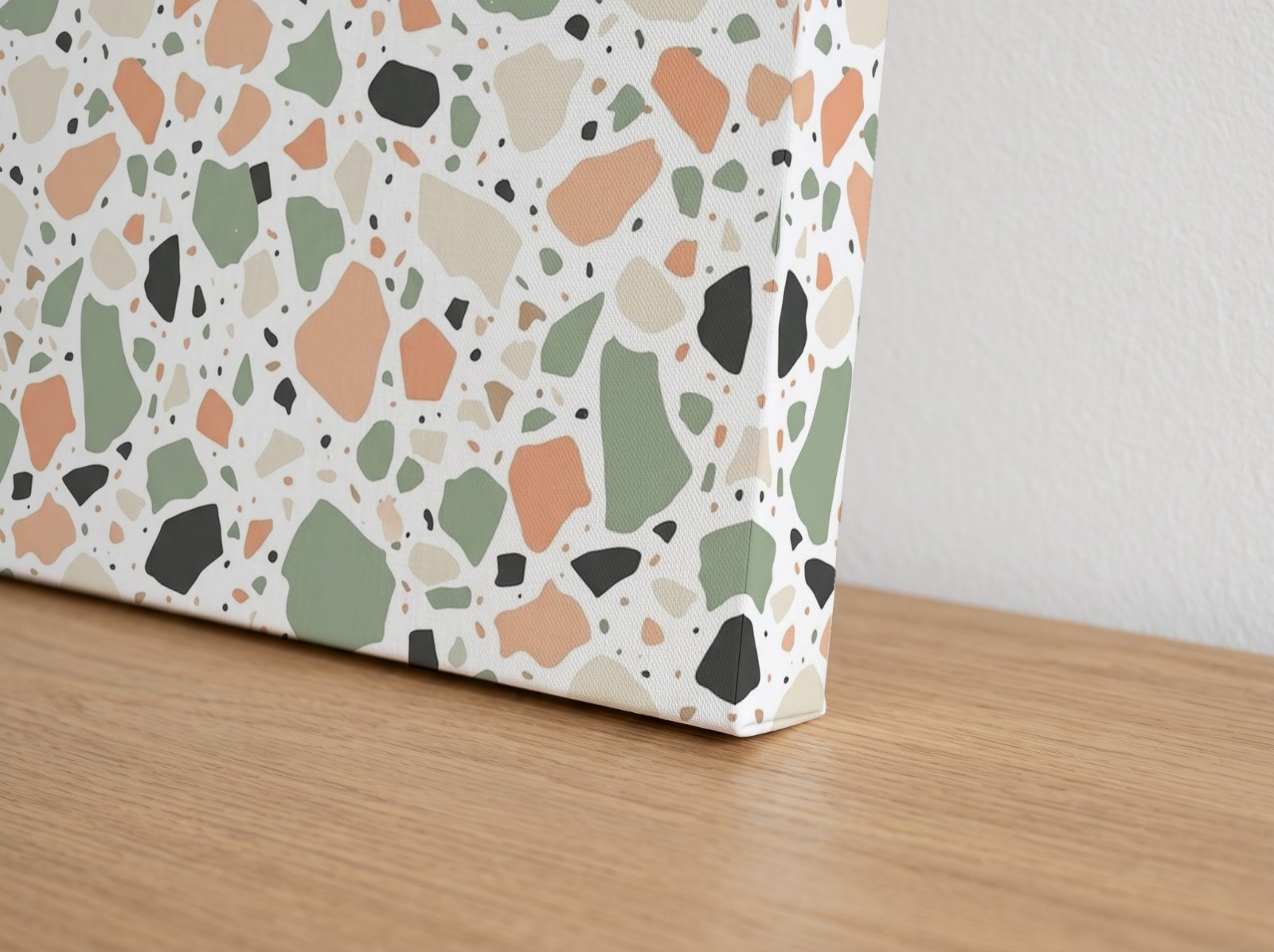 Corner close-up of a mirror edge canvas with a terrazzo pattern print on an oak sideboard