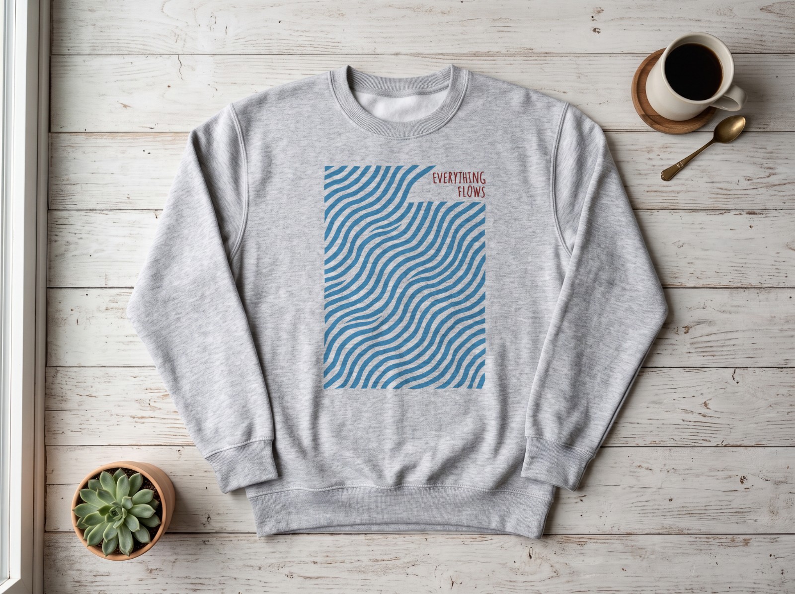 Grey Sweatshirt Flat Lay on White Wood showing an Everything Flows wave print