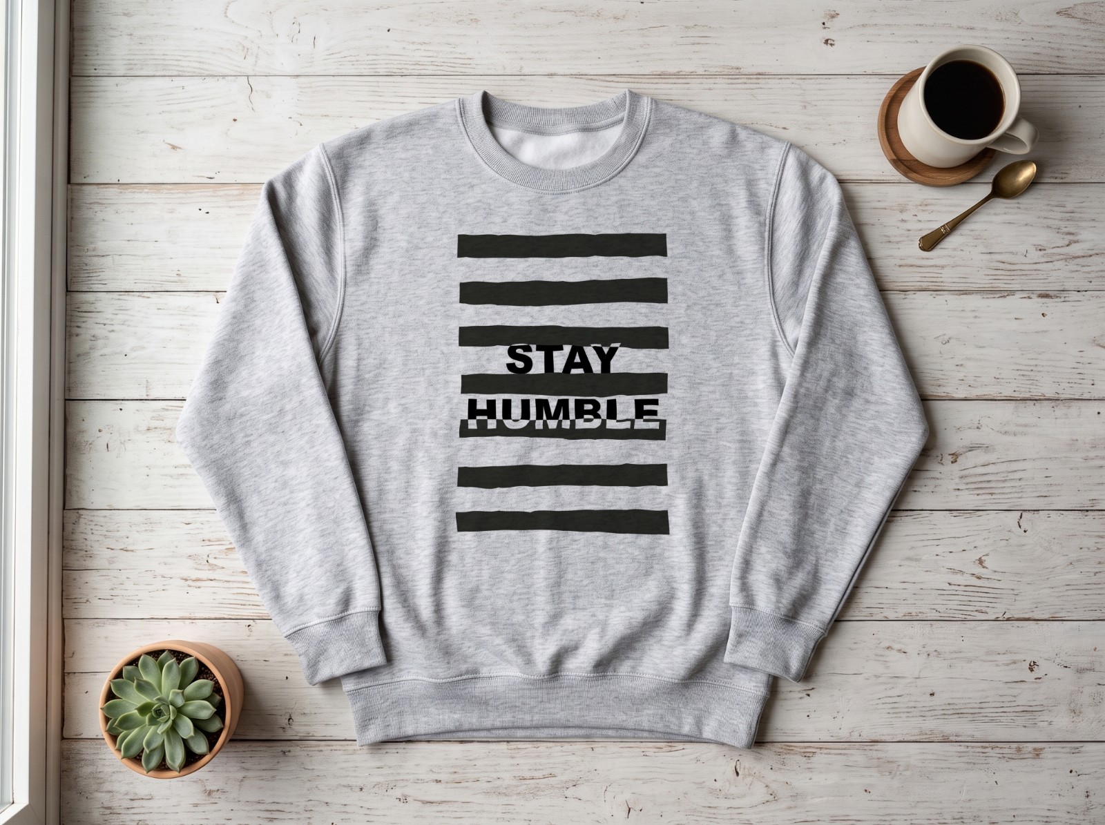 Grey Sweatshirt Flat Lay on White Wood showing a Stay Humble typography print