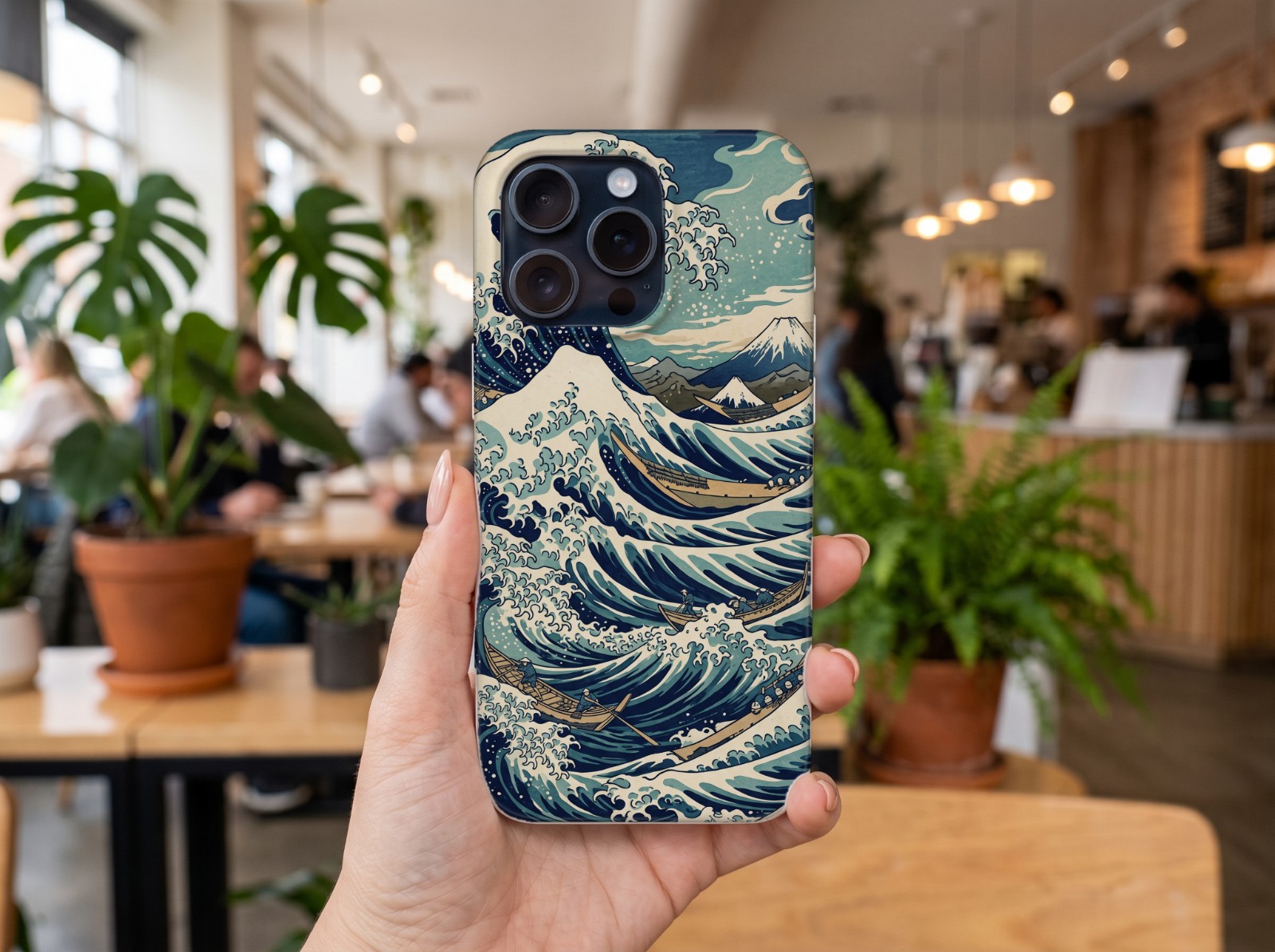 iPhone 15 Pro Case Held in a Hand in a Café showing a Japanese great wave print
