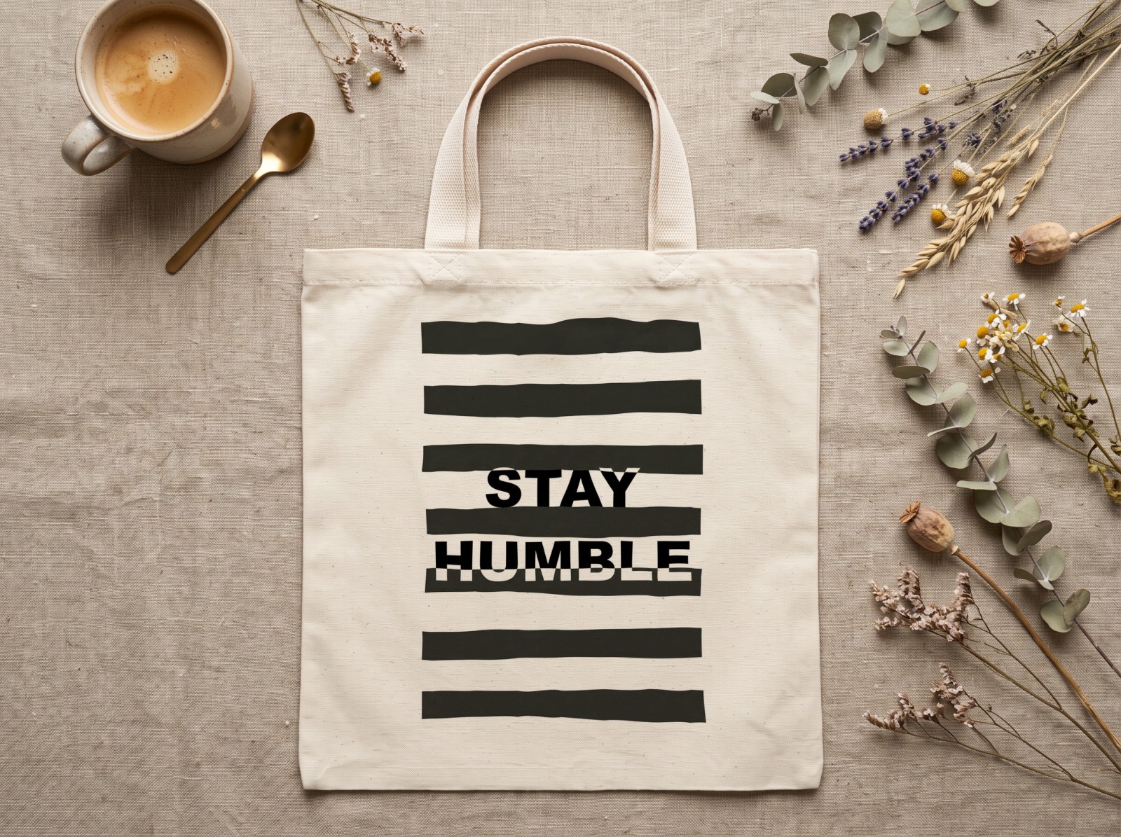 Natural Tote Bag Flat Lay on Linen with Dried Flowers showing a Stay Humble typography print