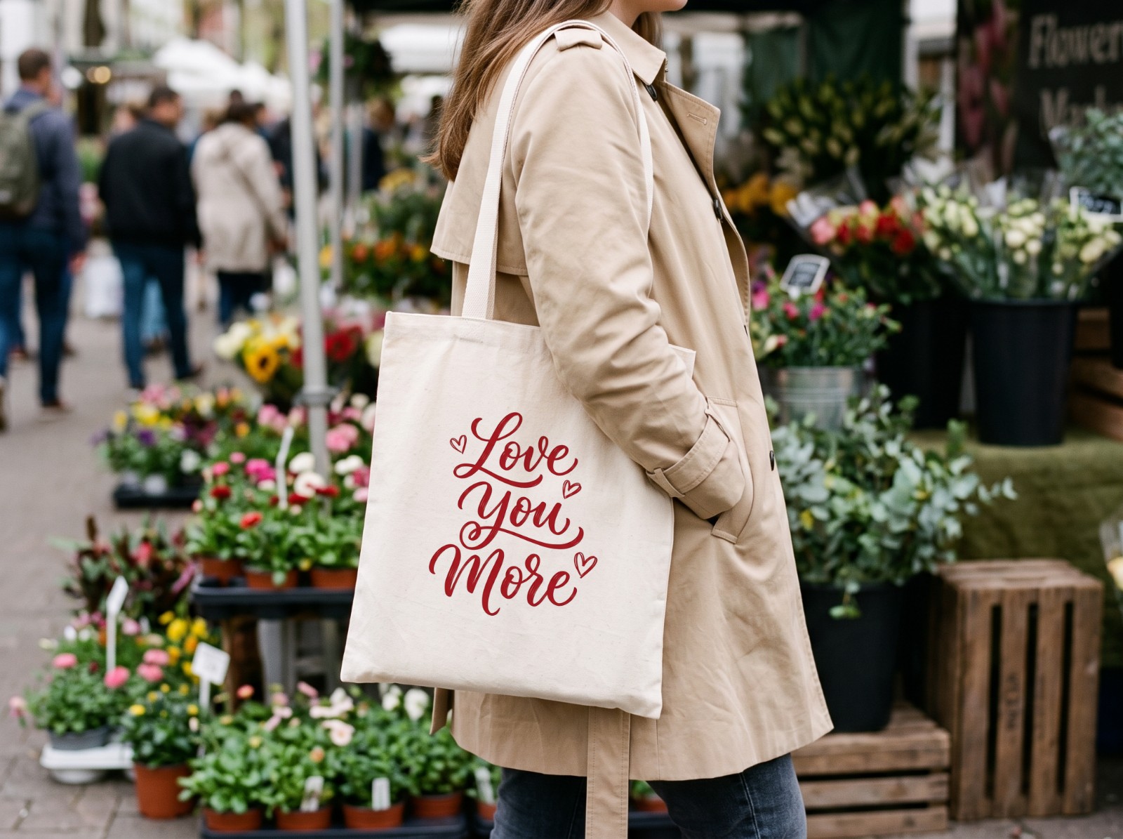Natural Tote Bag on a Woman's Shoulder at a Flower Market showing a Love You More lettering