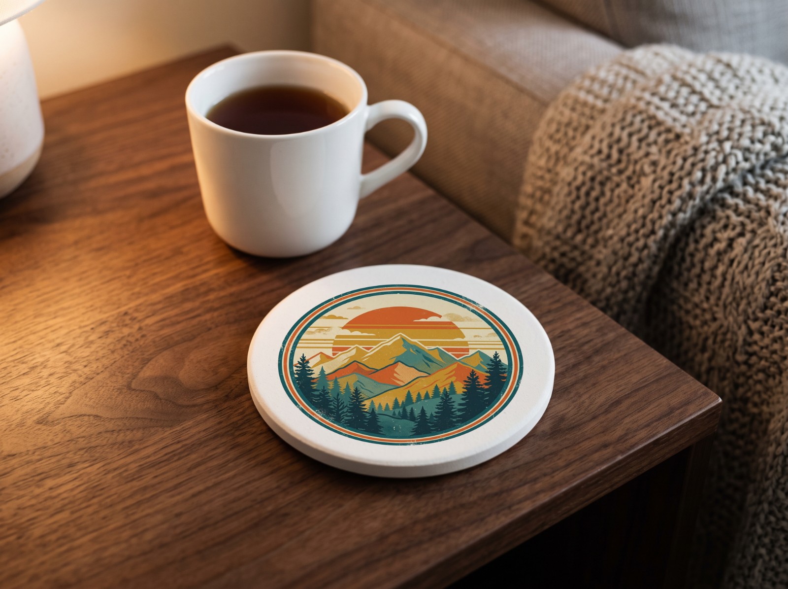 Round Sandstone Coaster on a Walnut Side Table with Tea showing a retro mountain sunset badge