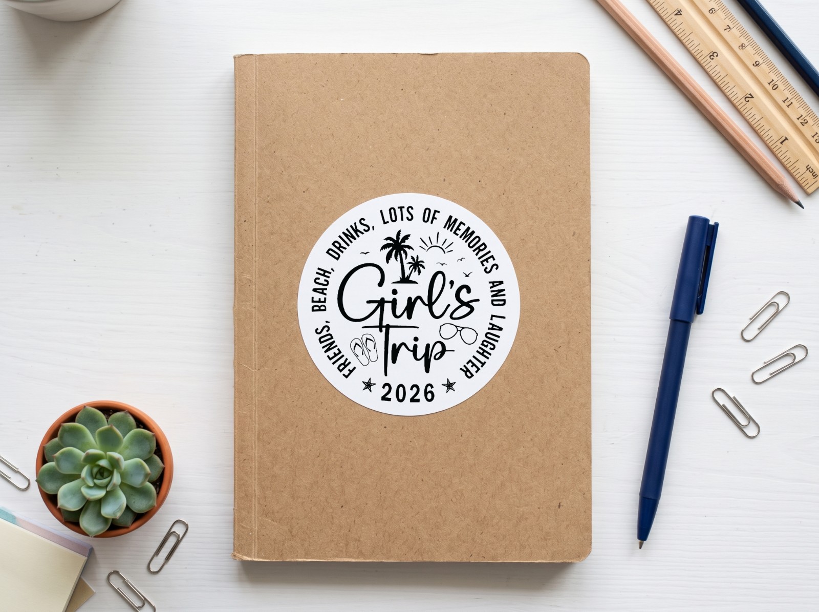Round Sticker on a Kraft Notebook showing the Girl's Trip 2026 design