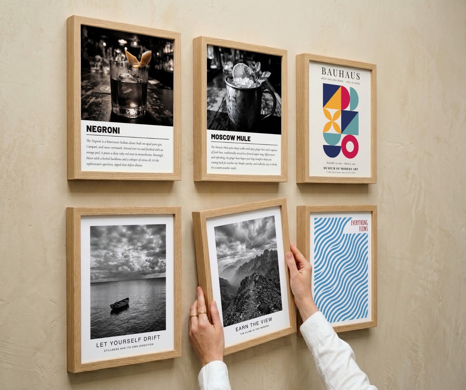 Six Oak Frame Gallery Wall, Angle View showing an Everything Flows wave print, a black and white mountain print and 4 more designs