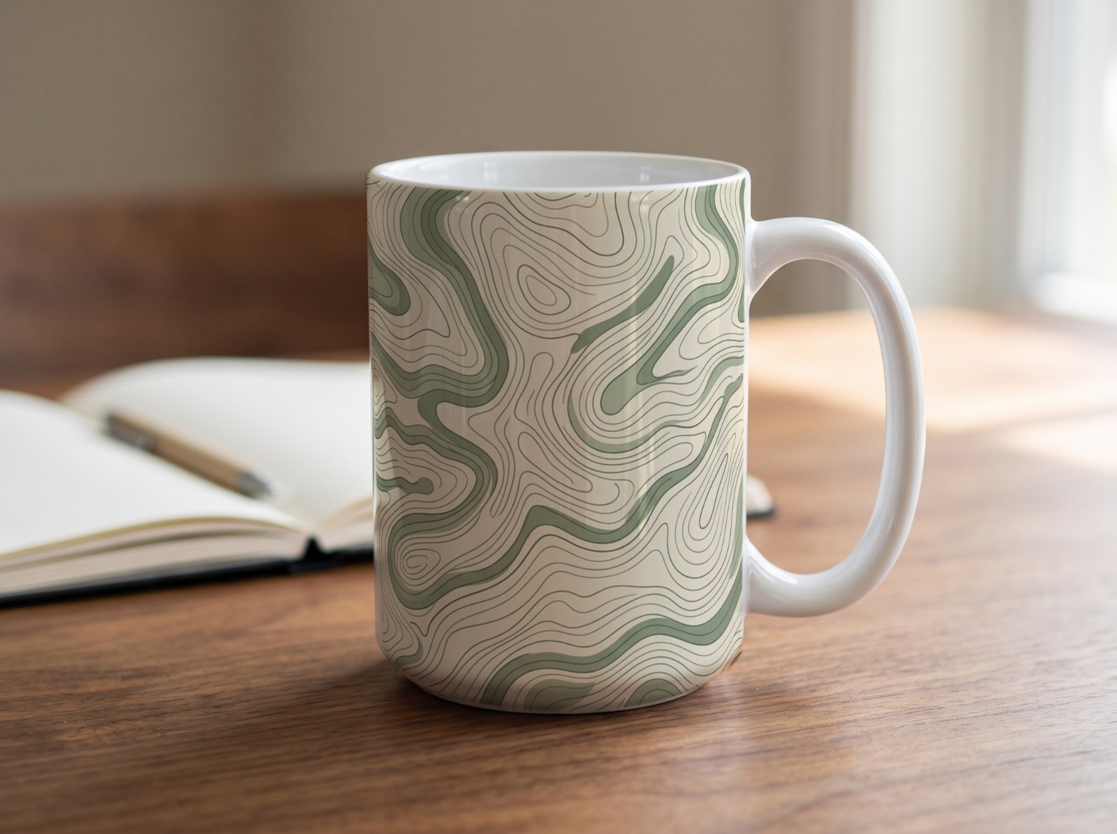 15 oz White Mug on a Walnut Desk with a Notebook showing a sage topographic map pattern