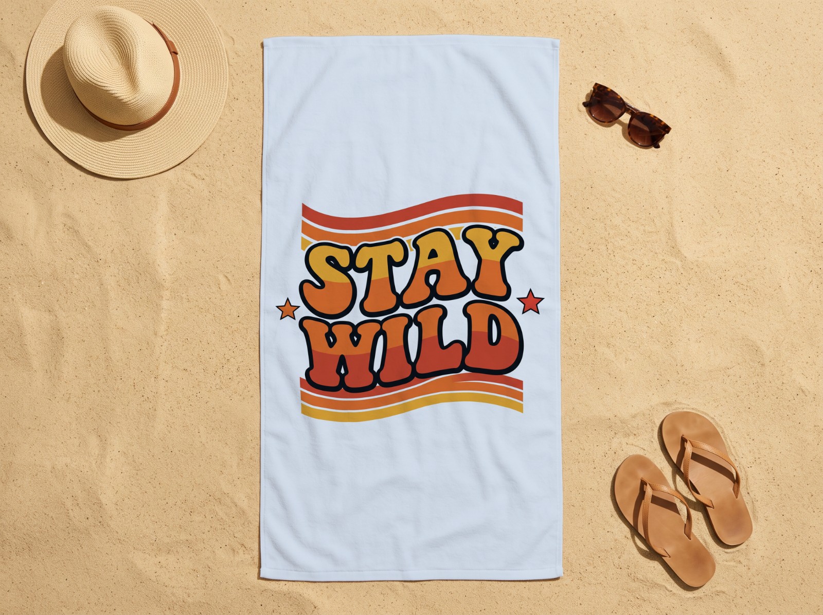 White Beach Towel on Sand with a Straw Hat showing the retro Stay Wild design