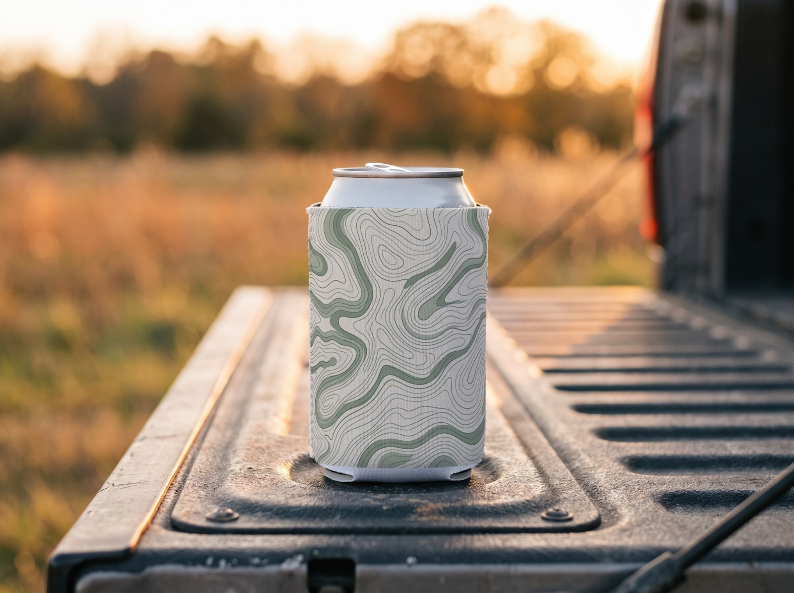 White Can Cooler on a Truck Tailgate at Sunset showing a sage topographic map pattern