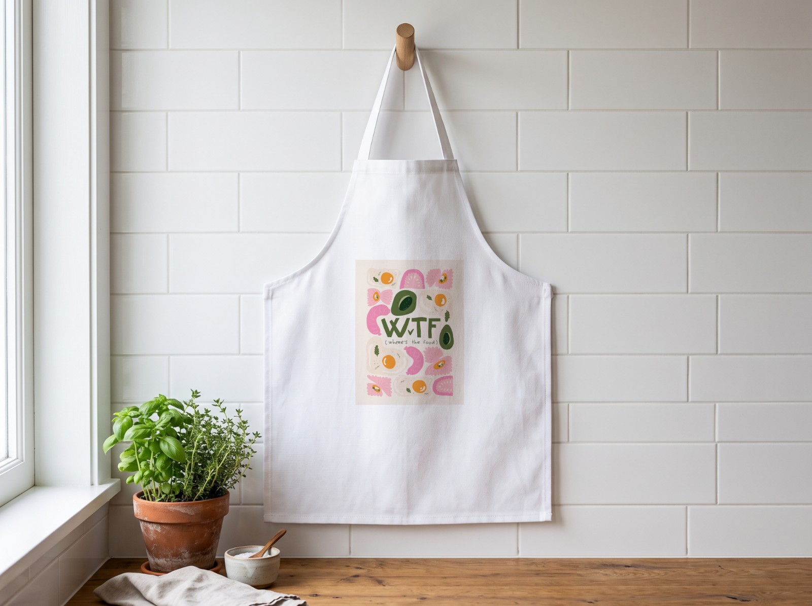 White Canvas Apron Hanging in a Kitchen showing the WTF (Where's the Food) print