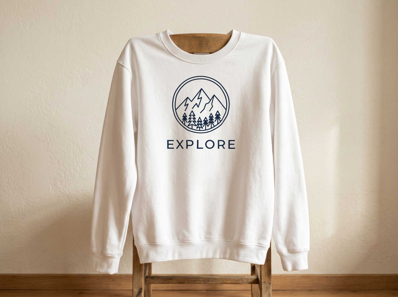 White Sweatshirt Hanging on a Wooden Chair showing an Explore mountain emblem