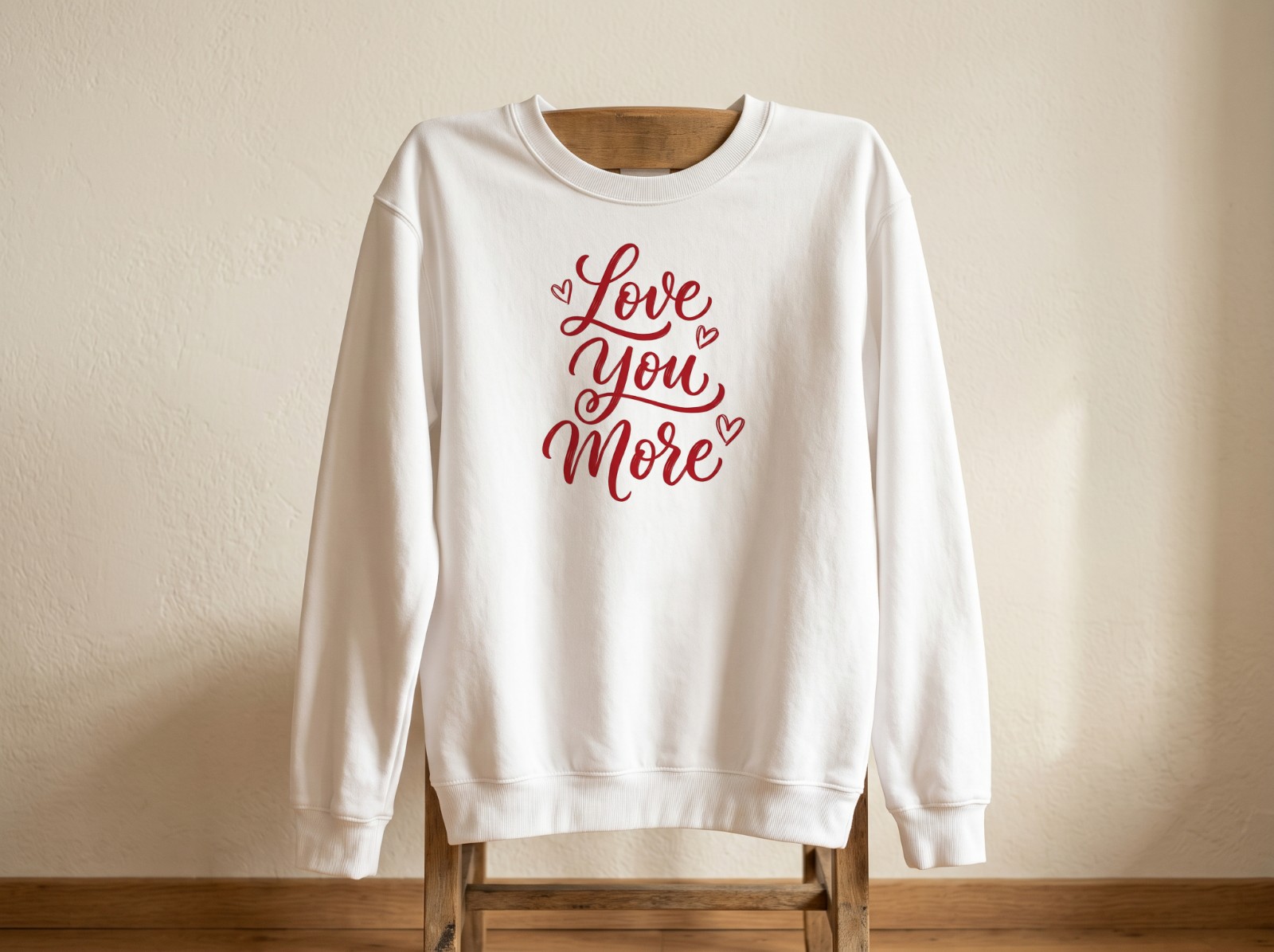 White Sweatshirt Hanging on a Wooden Chair showing a Love You More lettering