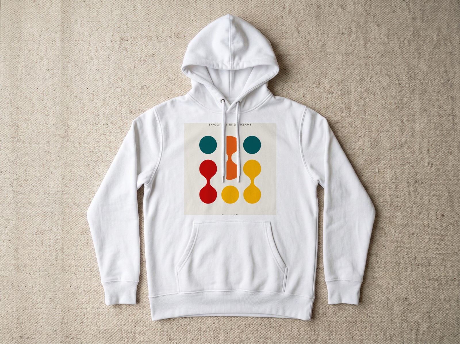 White Hoodie Flat Lay on a Beige Rug showing a Bauhaus Typografie print