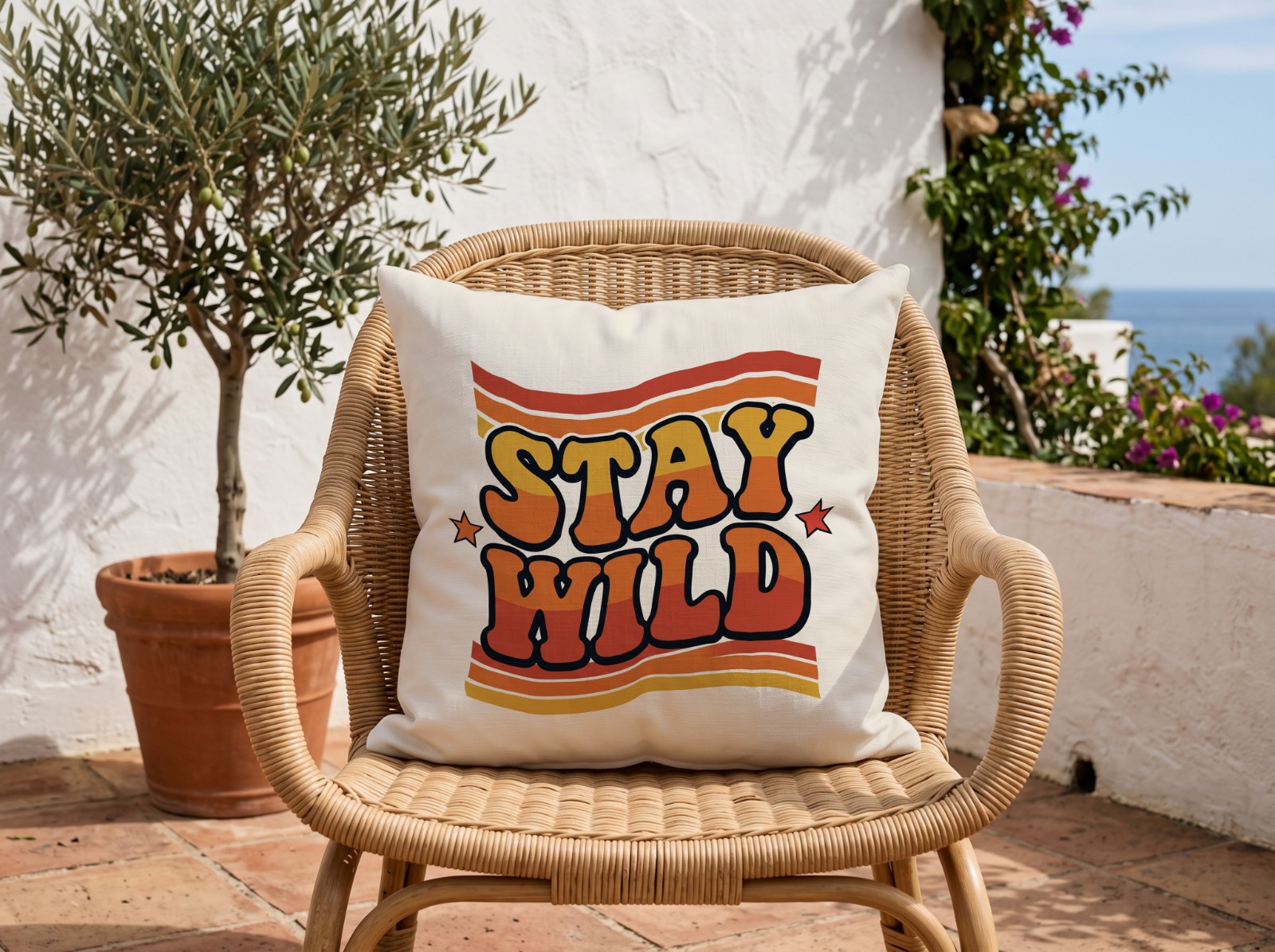 White Outdoor Pillow on a Rattan Chair on a Sunny Terrace showing the retro Stay Wild design