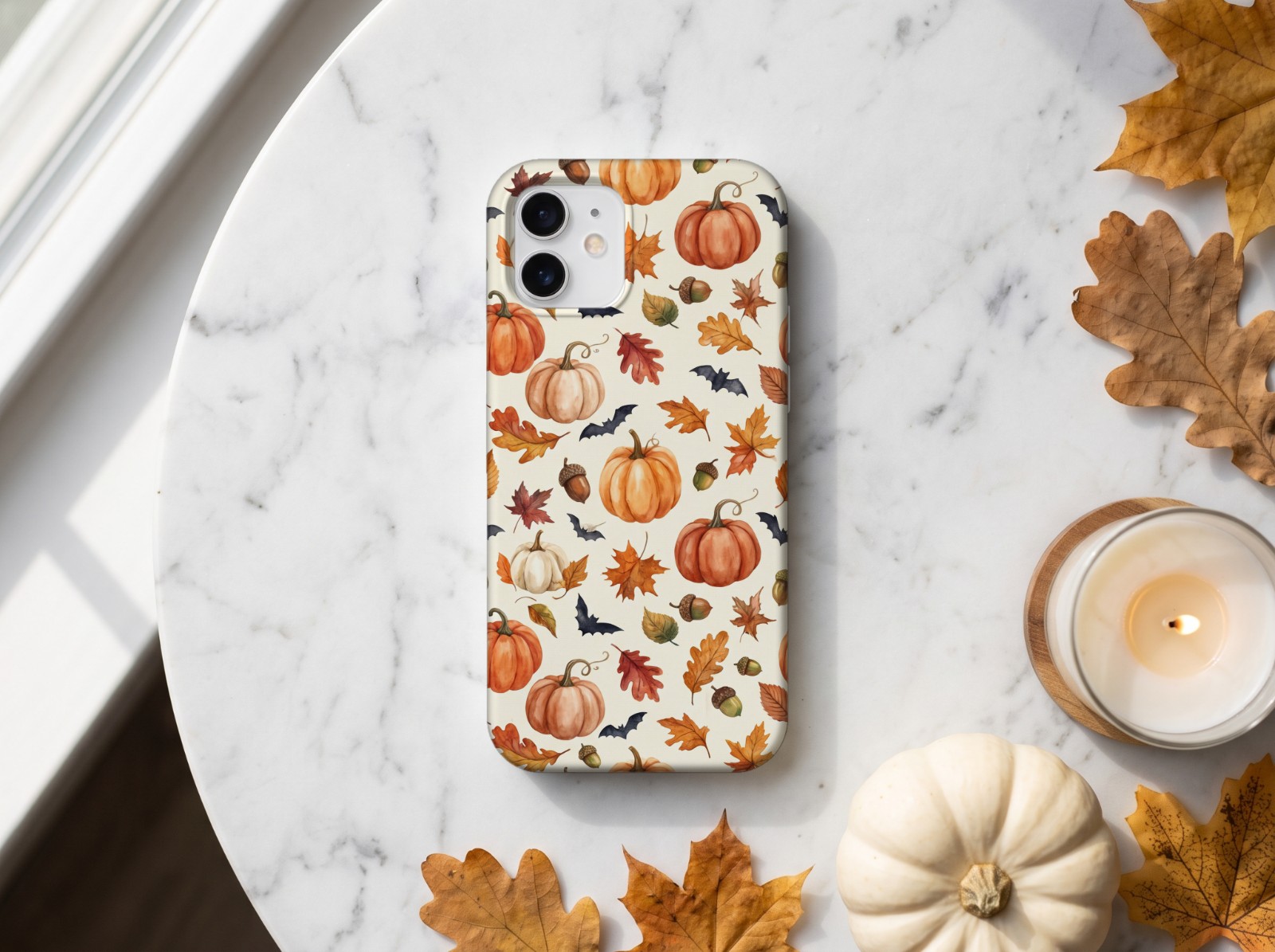 White Phone Case Halloween on Marble with a Pumpkin and Candle showing a watercolour pumpkin and autumn leaf pattern