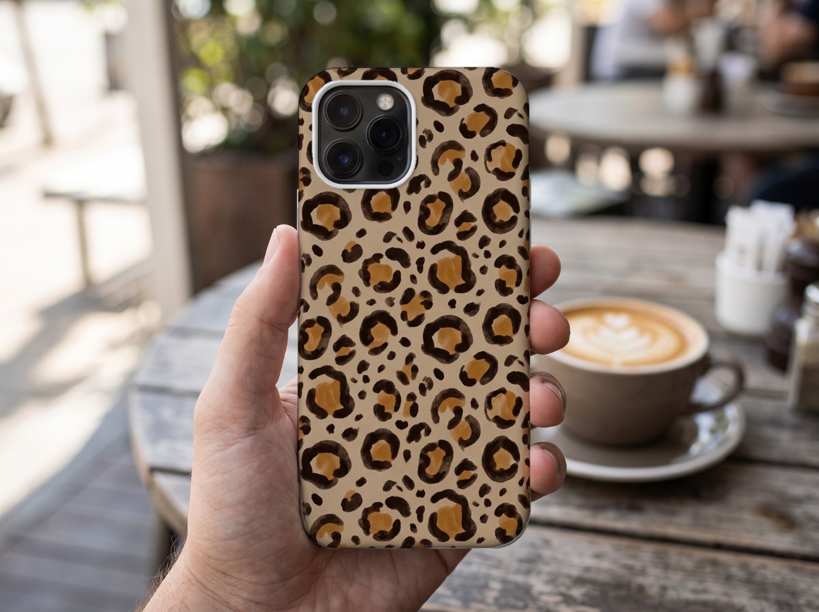 White Phone Case Held in a Hand at a Cafe showing a neutral leopard print