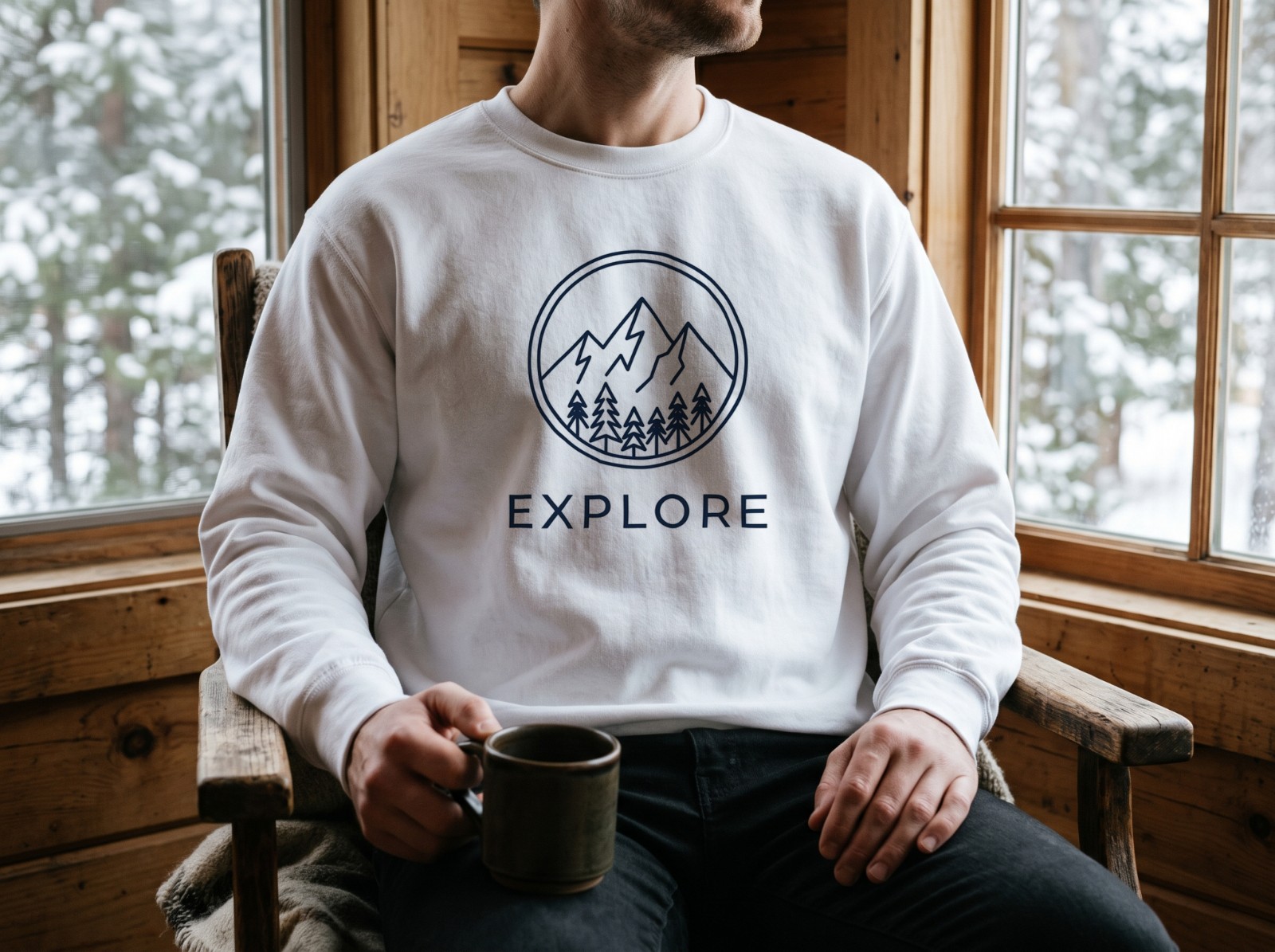White Sweatshirt on a Man in a Snowy Cabin showing an Explore mountain emblem
