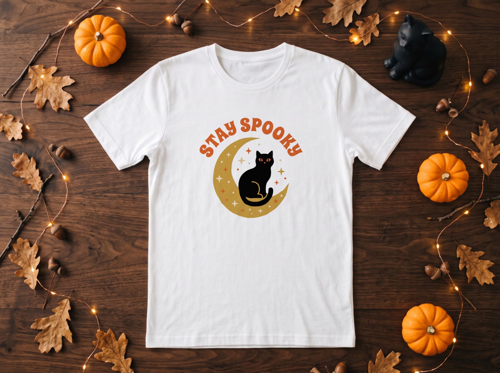 White T-Shirt Halloween Flat Lay with Black Cat and Pumpkins showing a Stay Spooky black cat and moon design