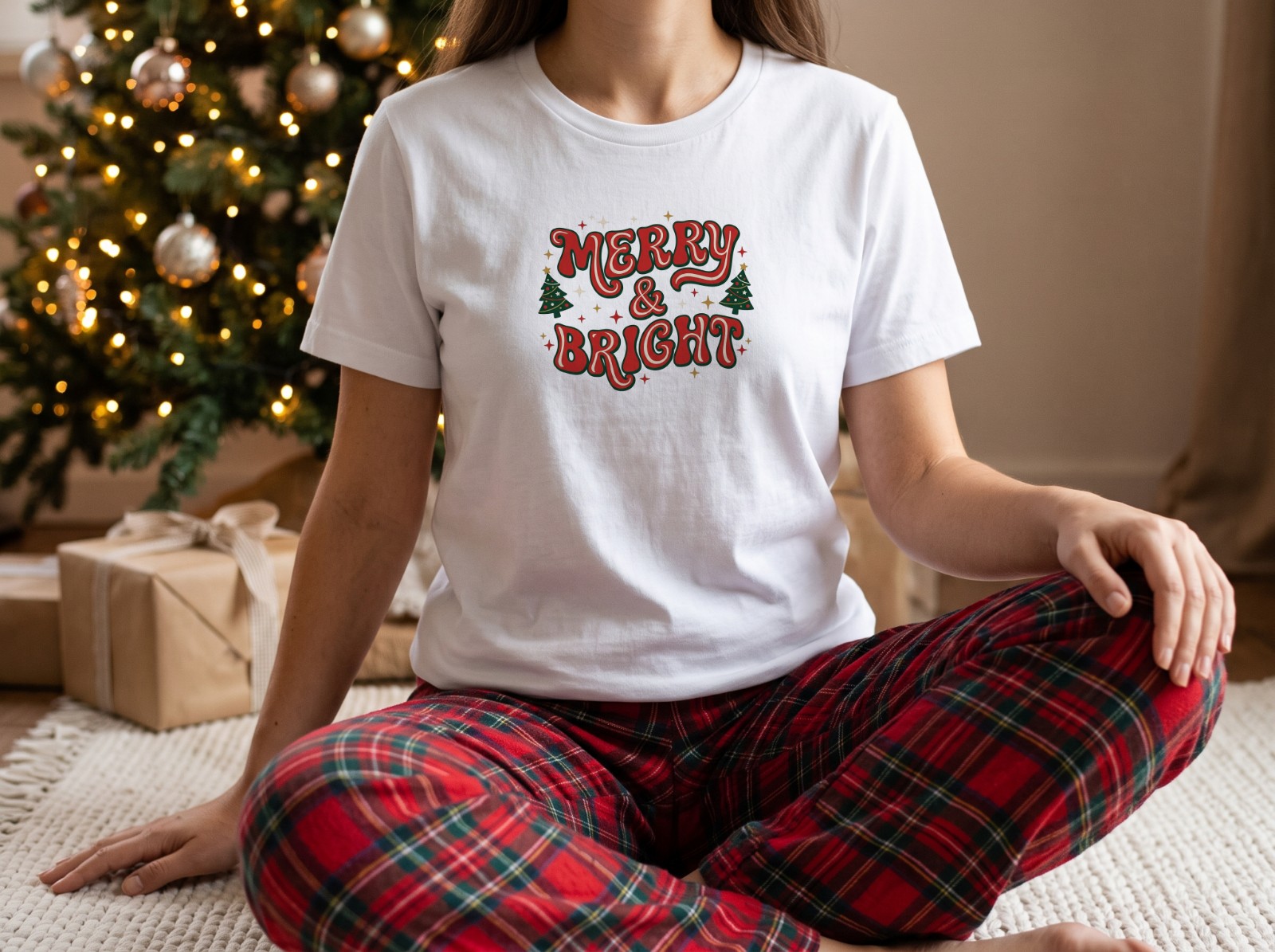 White T-Shirt Mockup on a Woman by a Christmas Tree in Plaid Pyjamas example