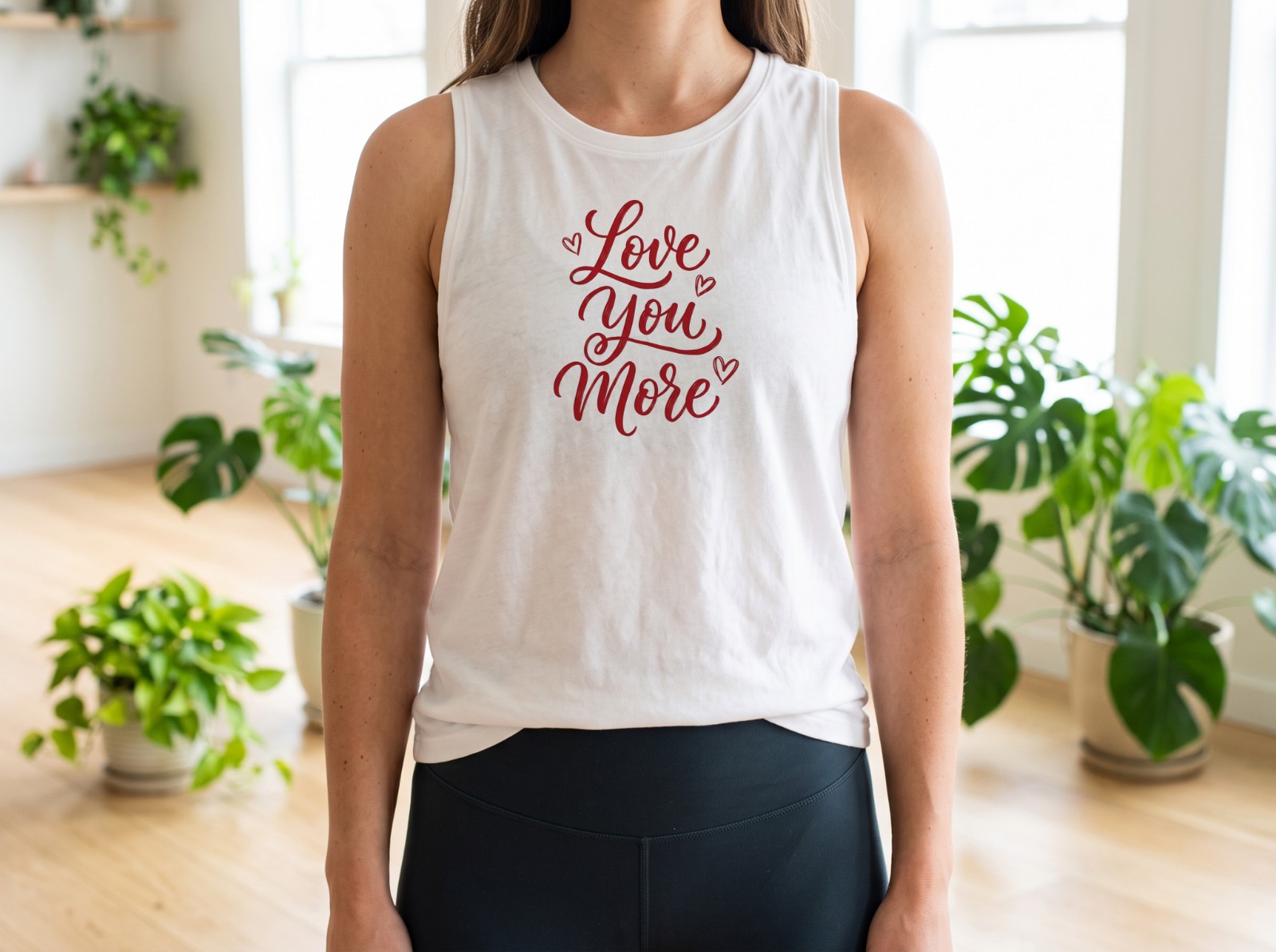 White Tank Top on a Woman in a Bright Yoga Studio showing a Love You More lettering