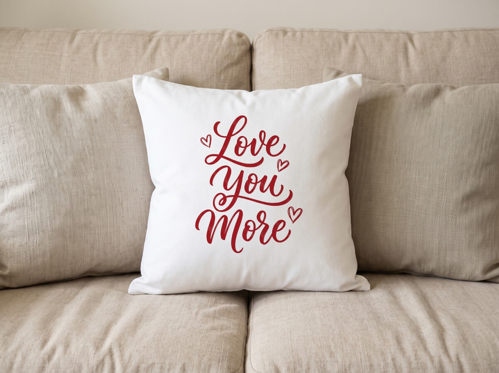 White Throw Pillow on a Beige Linen Sofa showing a Love You More lettering