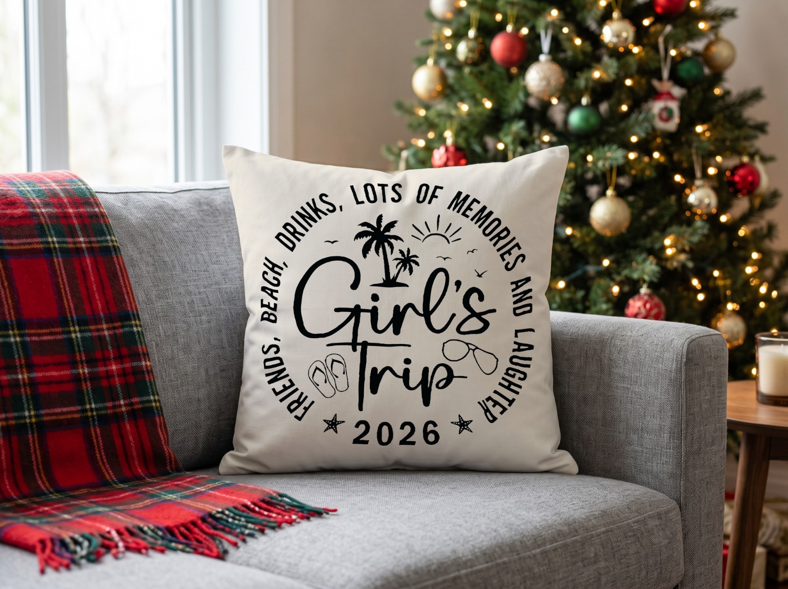 White Throw Pillow on a Grey Sofa by a Christmas Tree showing the Girl's Trip 2026 design