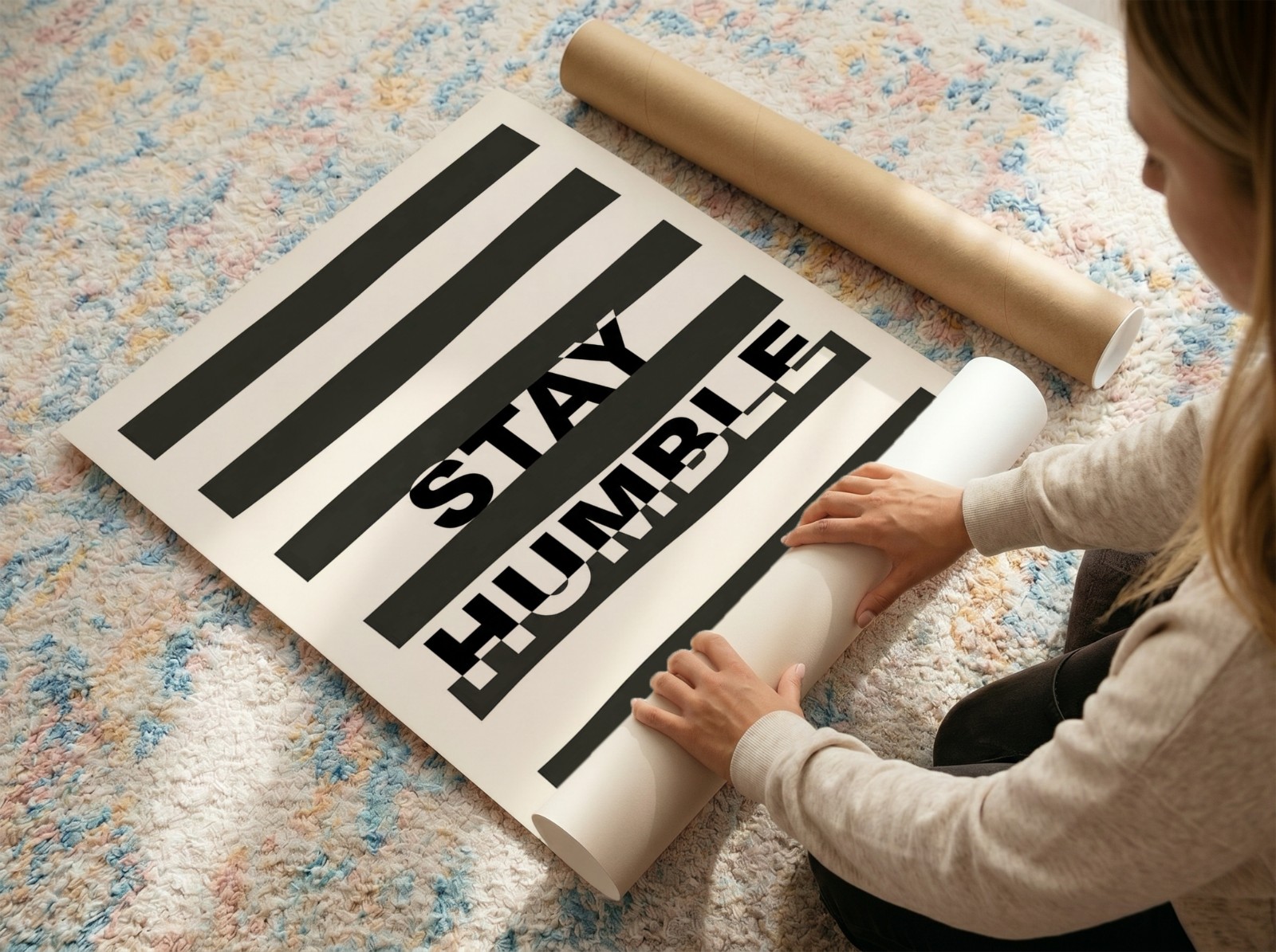 Woman Unrolling Poster on Colourful Rug showing a Stay Humble typography print